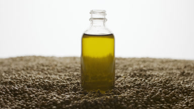 Crane shot of reagent bottle with yellow liquid on hemp seeds