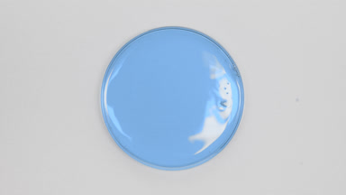 Big close-up of blue oil in Petri dish on grey background