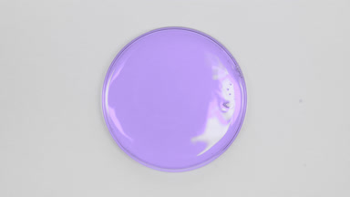 Big close-up of purple oil in Petri dish on grey background