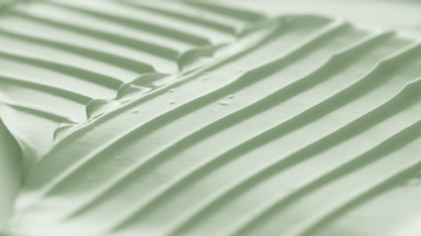 Macro turntable crane shot of pale green cosmetic cream