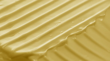Side view macro turntable shot of pale yellow cosmetic cream