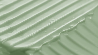 Side view macro turntable shot of pale green cosmetic cream