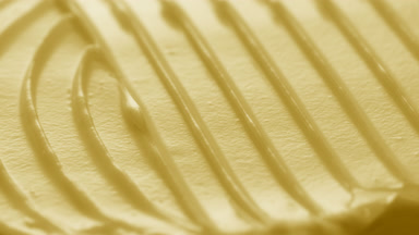 Macro turntable crane shot of yellow cosmetic cream texture