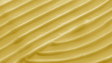 Side view macro turntable shot of yellow cosmetic cream surface