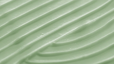 Side view macro turntable shot of green cosmetic cream surface