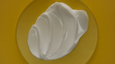 Top view of white cream on glass round with changing lighting