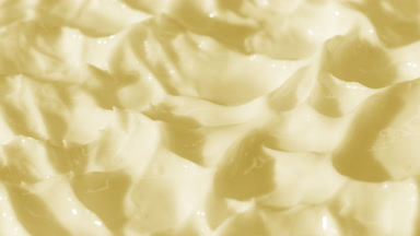 Side view macro turntable shot of yellow cosmetic cream texture