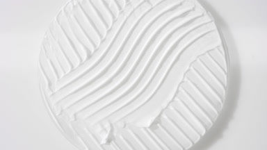 Crane shot of white cream on glass round on white background