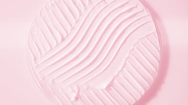 Crane shot of pink cream on glass round on pale pink background