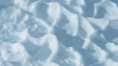 Side view macro turntable shot of blue day cream surface