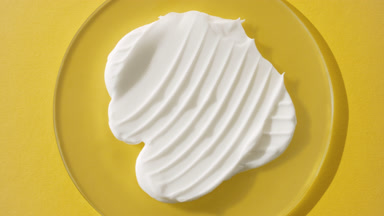 Jib shot of white cream on watch glass on yellow background
