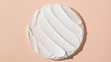 White anti-aging cream on watch glass on beige background