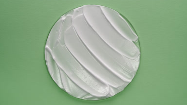 White hydrating cream on watch glass on green background