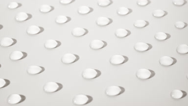 Macro crane shot of moving transparent drops on white background