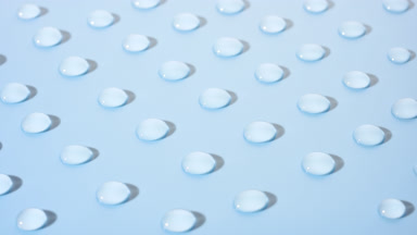 Macro crane shot of moving transparent drops on blue background