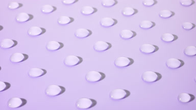 Crane shot of moving transparent drops on violet background