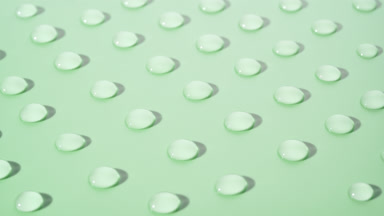 Macro crane shot of moving transparent drops on green background