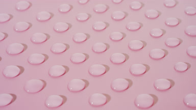 Macro crane shot of moving clear drops on pink background