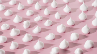 Drops of white cream on pink background with moving lighting