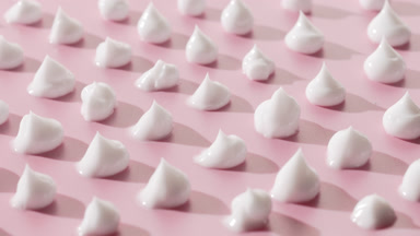 Crane turntable shot of white cream drops on pink background