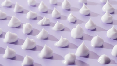Crane turntable shot of white cream drops on violet background