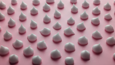 Jib shot of drops of white cream on pink background in shadow