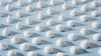 White cream drops on blue background with moving light source