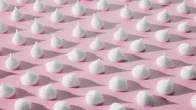 White cream drops on pink background with moving light source