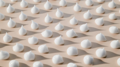 White cream drops on beige background with moving light source