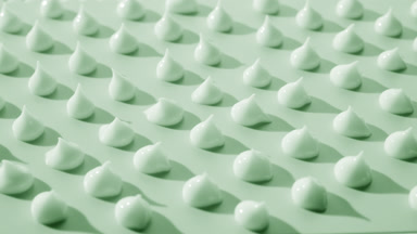 Multiple drops of green cream on green background