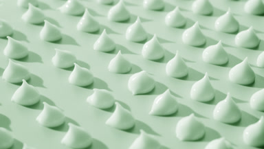 Multiple drops of green day cream on green background