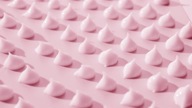 Side view of drops of pink cosmetic cream on pink background