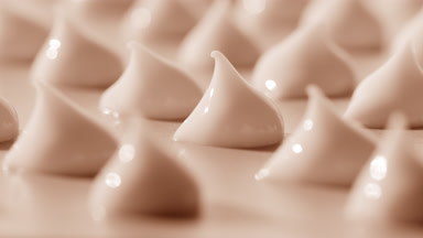 Macro of multiple drops of beige day cream on beige background