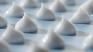 Macro of drops of white cosmetic cream on pale blue background
