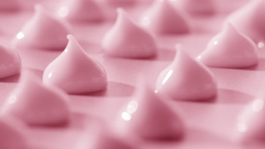 Macro of drops of pink cream with rose oil on pink background
