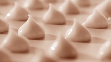 Macro of drops of beige cosmetic cream on beige background