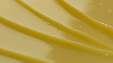 Yellow body care cream furrow texture with a reflection of light