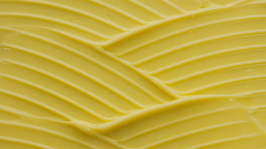 Macro crane shot of yellow day cream with collagen wave texture