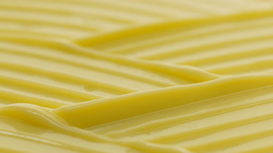 Macro crane shot of yellow moisturizing cream wave texture