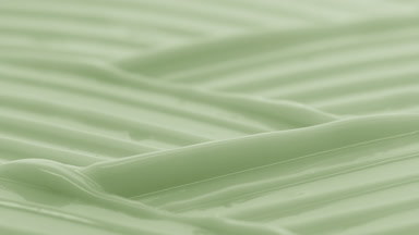 Macro crane shot of green moisturizing cream wave texture