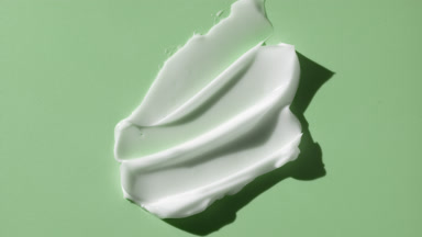 Macro crane shot of whitening cream smears on green background