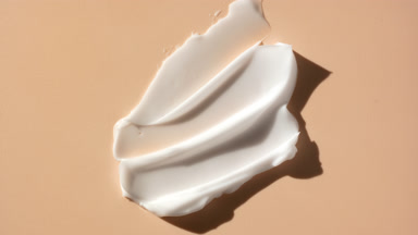Macro crane shot of whitening cream smears on beige background