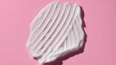 Macro of white cream smear furrow texture on pink background