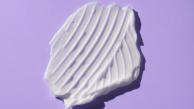 Macro of white cream smear furrow texture on purple background