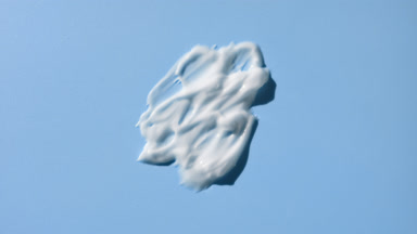 Macro of white cosmetic lotion smears on pale blue background