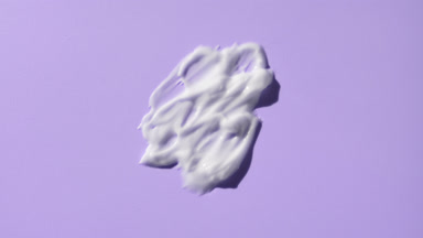 Macro of white cosmetic lotion smears on purple background
