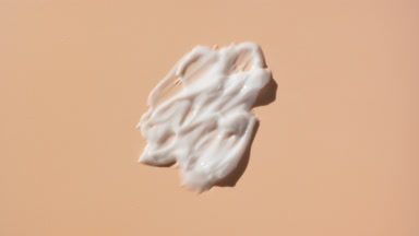 Macro of white cosmetic lotion smears on beige background