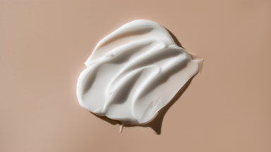 Macro crane shot of white face cream smears on beige background