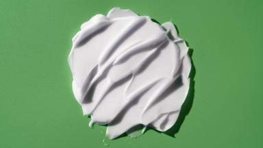 Macro crane shot of nourishing cream smears on green background