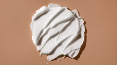 Macro crane shot of nourishing cream smears on beige background